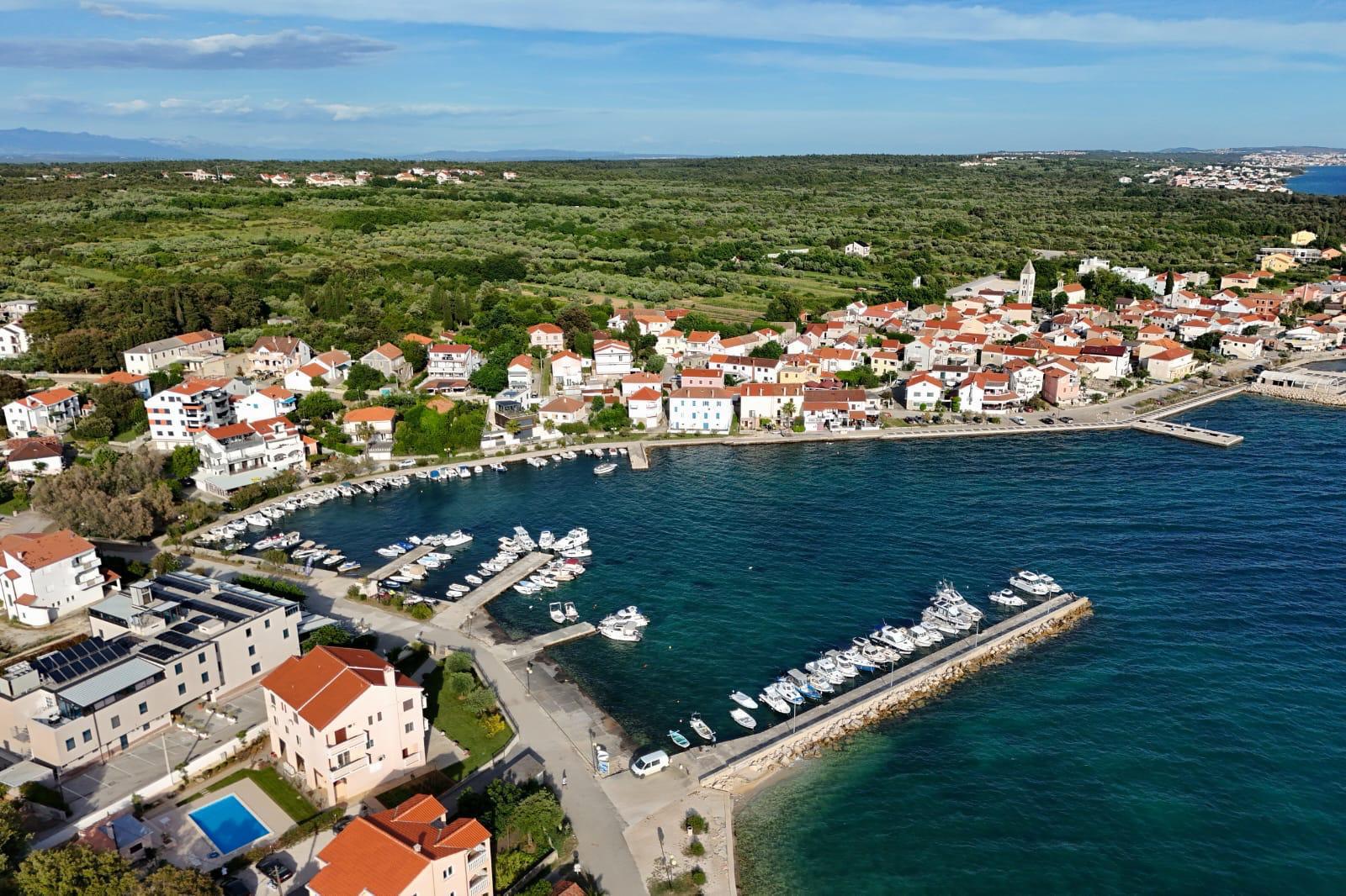 Petrčane iz zraka — luka s brodicama, riva i kamene kuće mjesta uz more