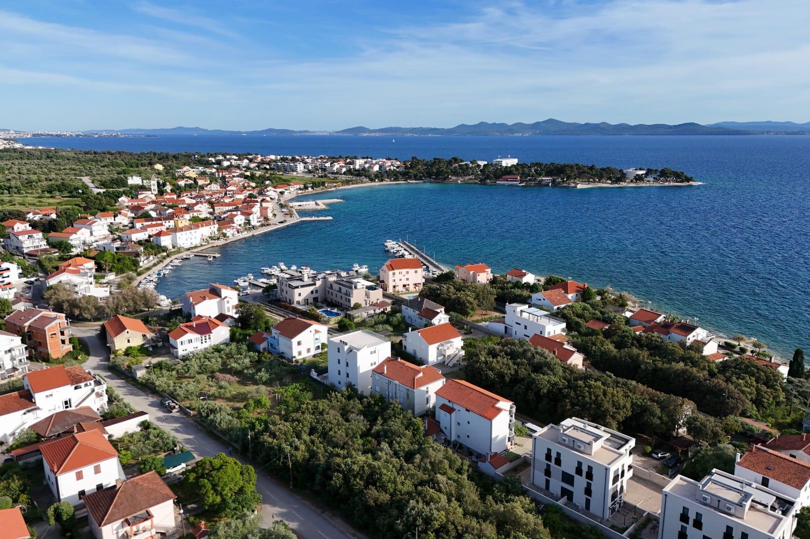 Uvala Petrčane iz zraka — luka s brodicama, poluotok s borovom šumom i Zadar u daljini